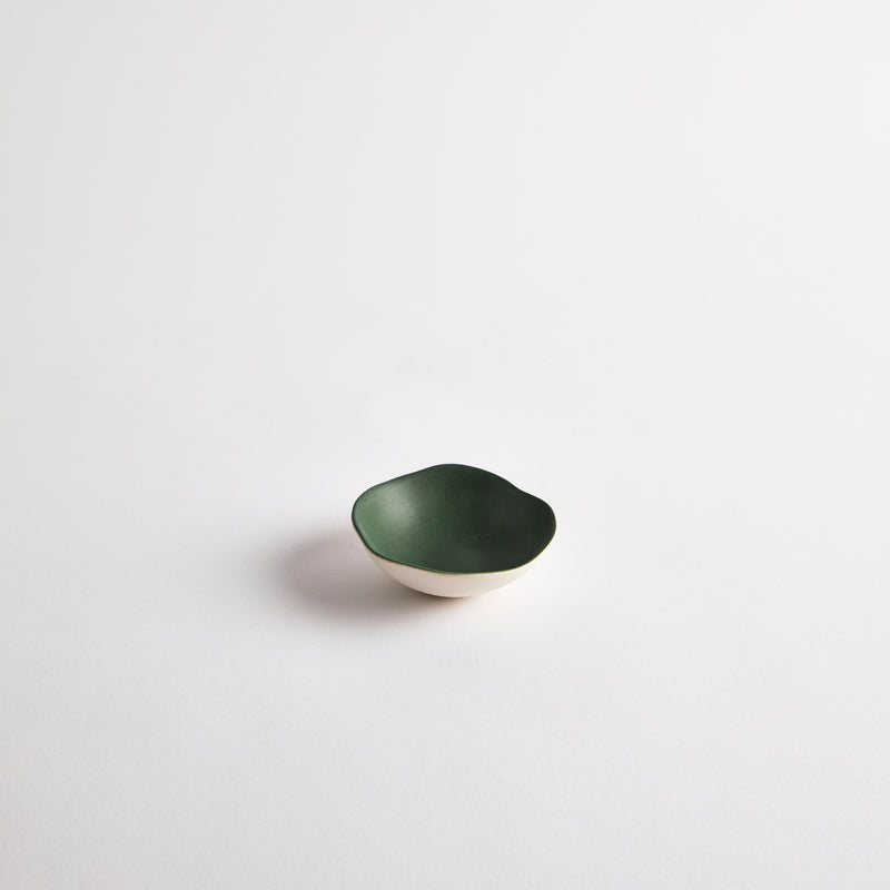 White mini ceramic dish with dark green interior.