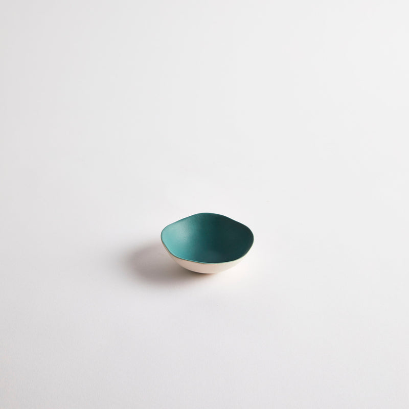 White mini ceramic dish with teal interior.