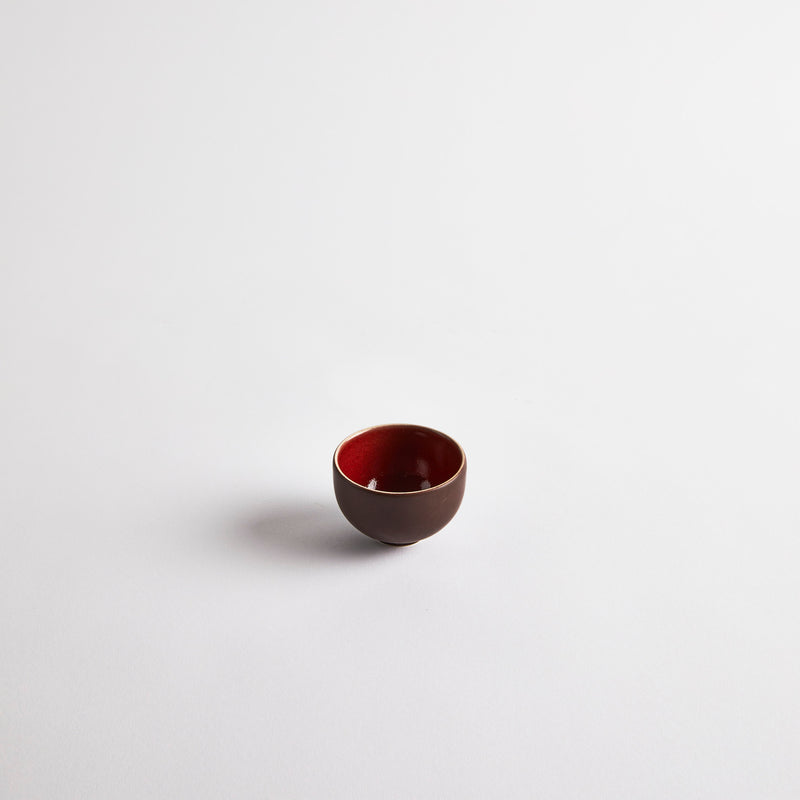 Brown pinch pot with red interior.