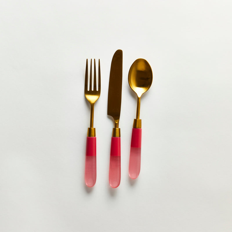 Gold serving cutlery with pink handle.