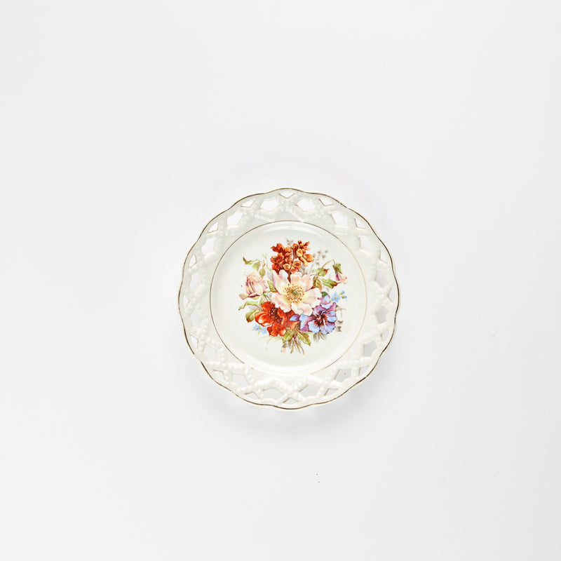 White plate with multicolour flower detail and lace cut design edge.