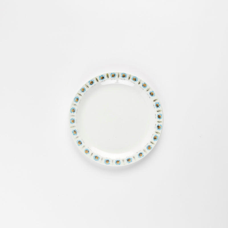White plate with blue and yellow flower and green leaf detail rim.
