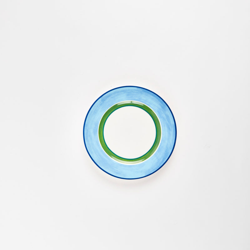 White plate with blue rim and green circle in center.