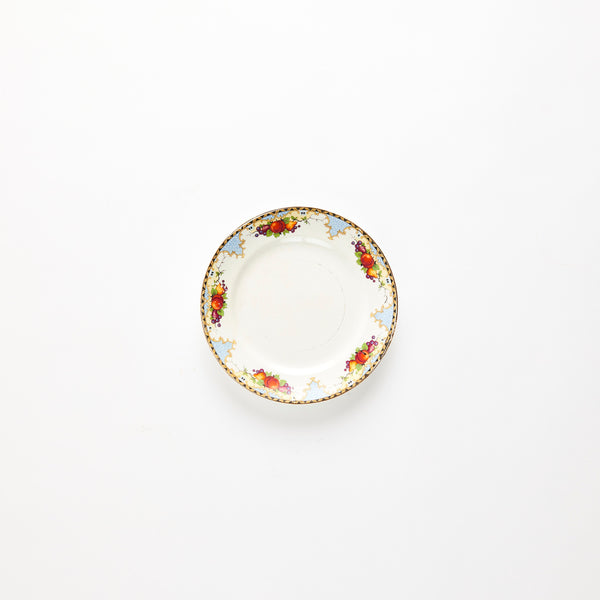Vintage white plate with decorative fruit pattern edge.