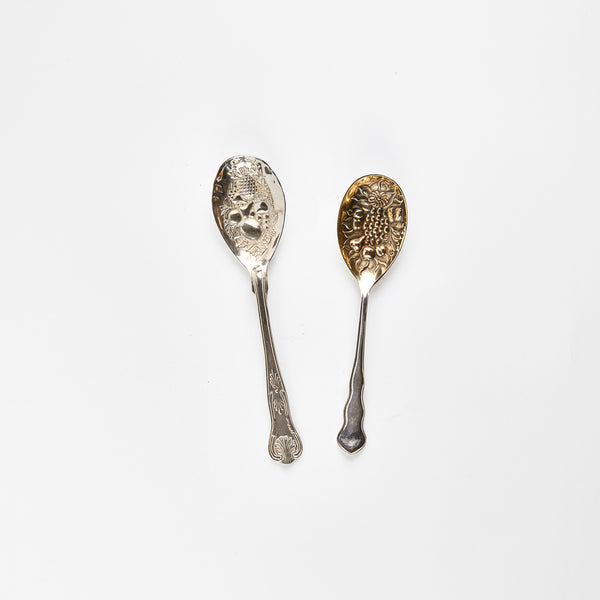 Two silver serving spoons with embossed designs.