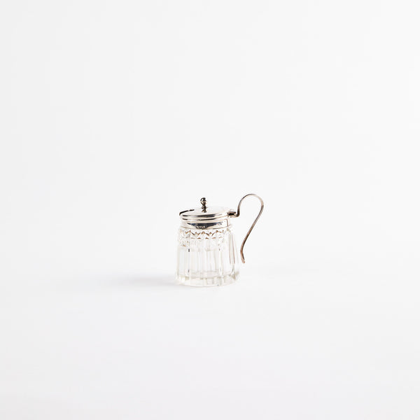 Clear glass shaker with metal top and handle.