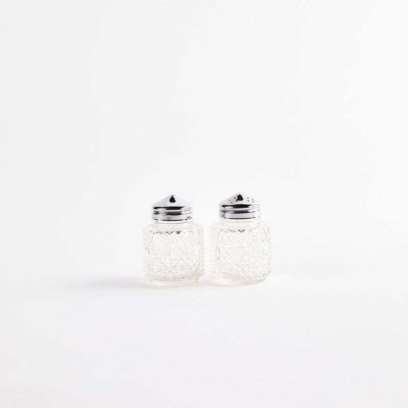 Clear glass shakers with metal tops.