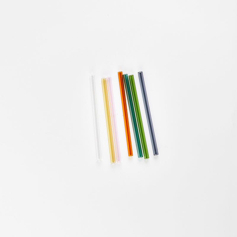 Clear, yellow, pink, amber, two green and grey glass straws.