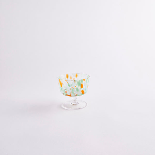 Clear glass coupe with orange, green and blue spots.