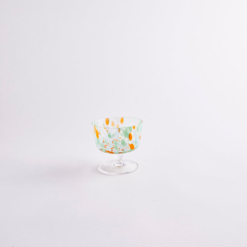Clear glass coupe with orange, green and blue spots.