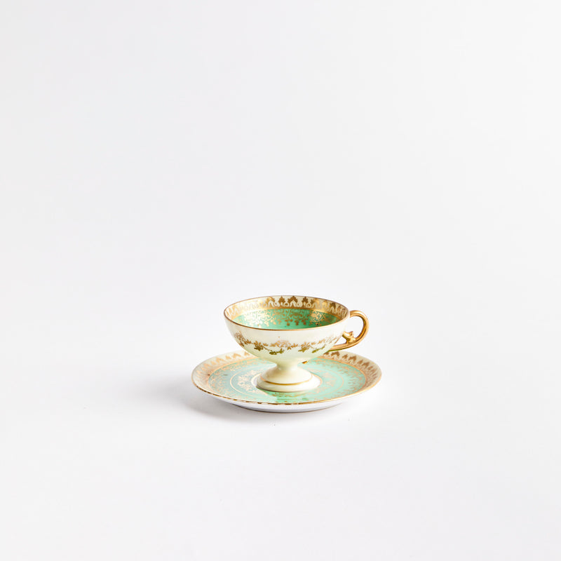 White teacup with green and gold design with saucer.