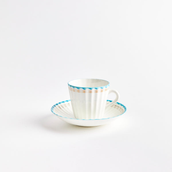 White teacup and saucer with blue and gold detailing.