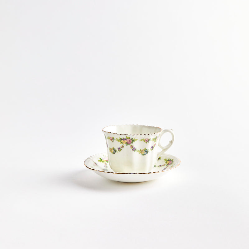 White teacup  and saucer with multicolour flowers.
