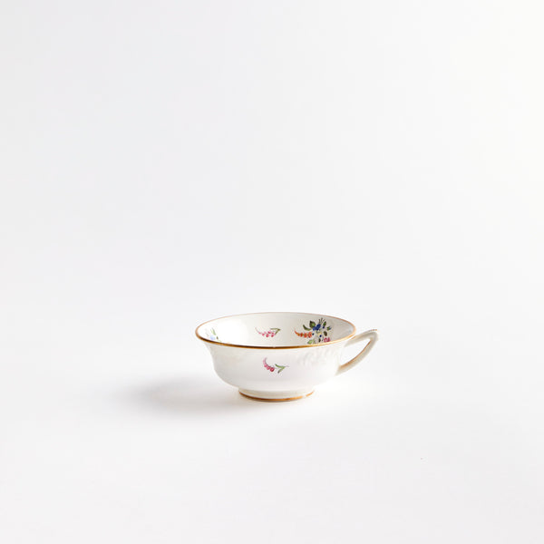 White teacup with floral and gold detail.