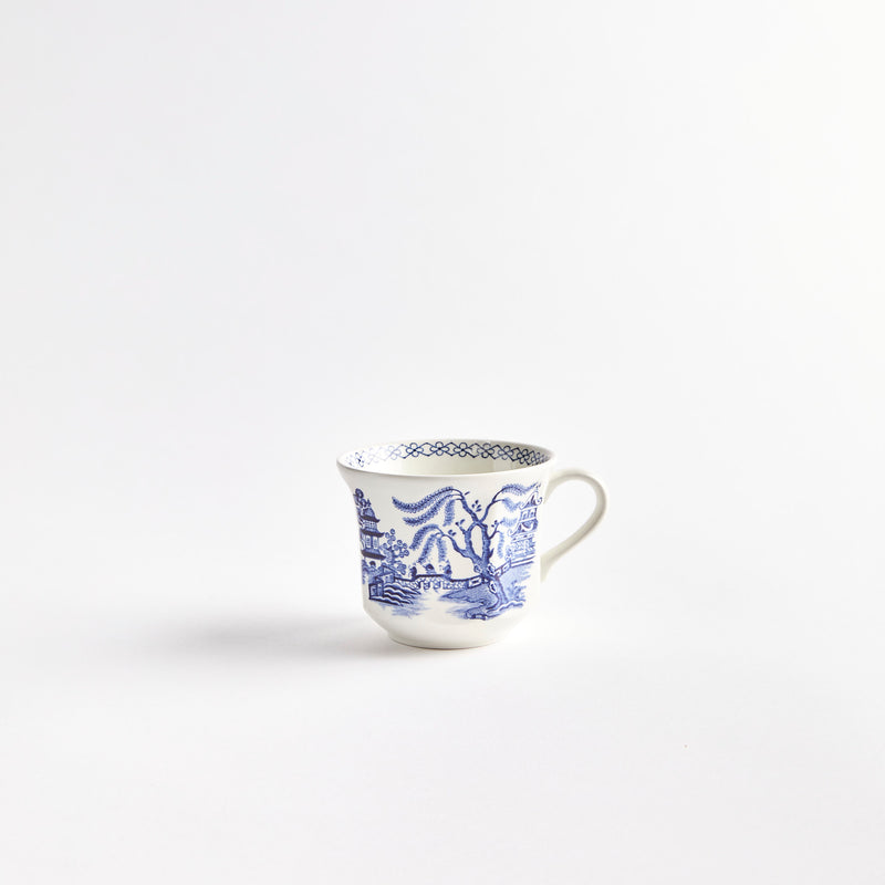 White teacup with blue house and field setting.