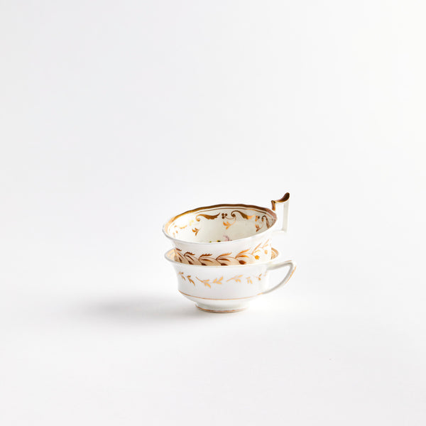 Two white teacups with gold detail. 