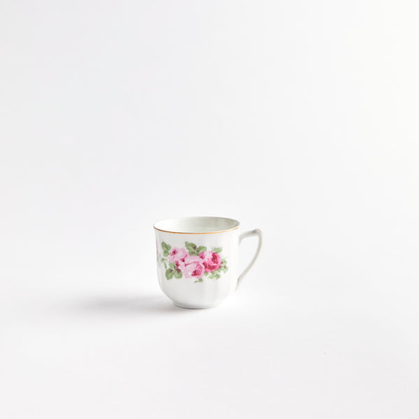 white teacup with pink flowers and gold detail.