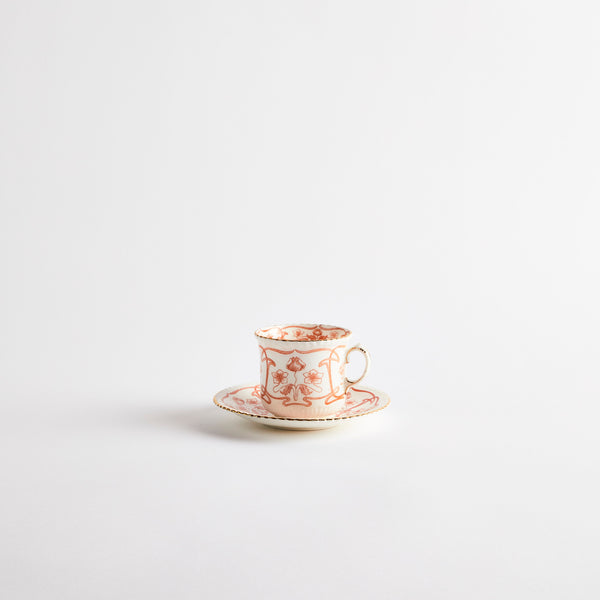 White teacup with orange floral design and gold rim.