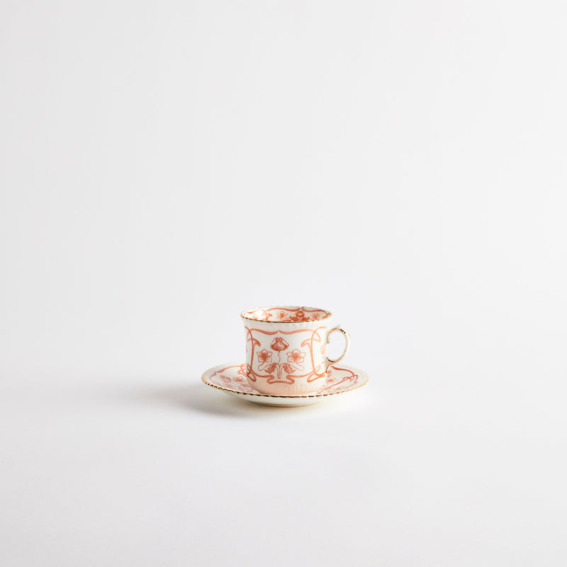 White teacup with orange floral design and gold rim.