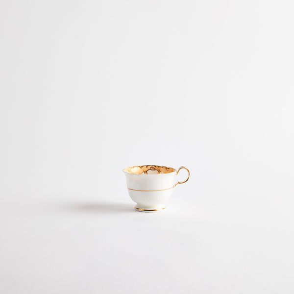 White teacup with gold detail and orange floral design inside.