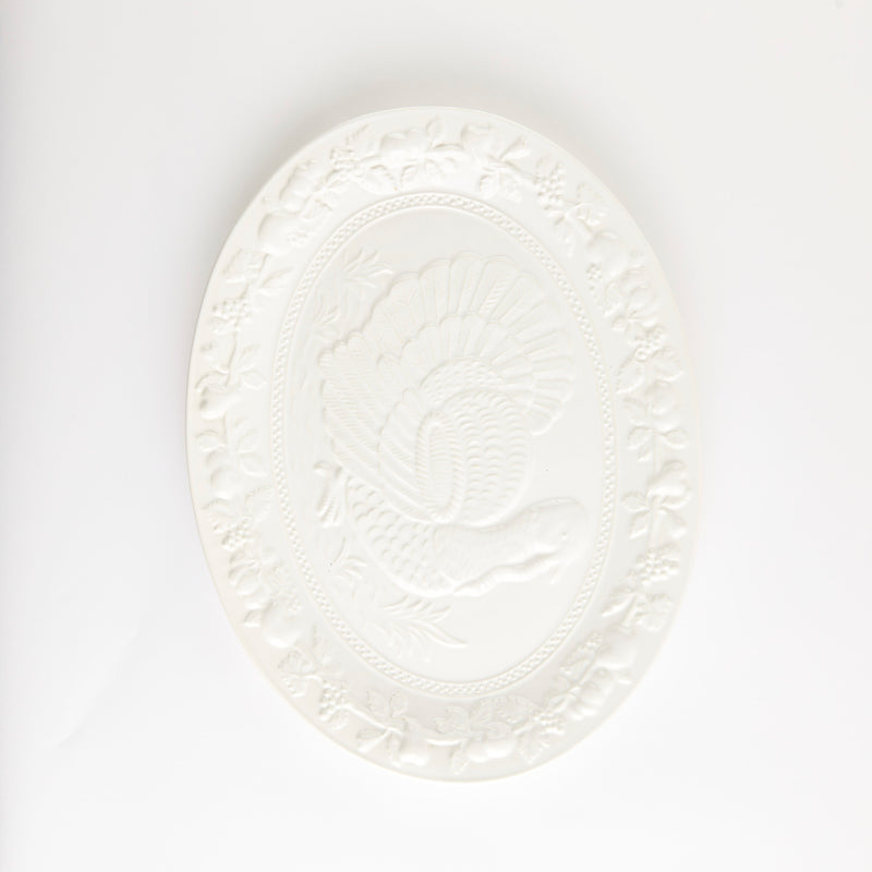 White platter with embossed turkey and vegetable design.