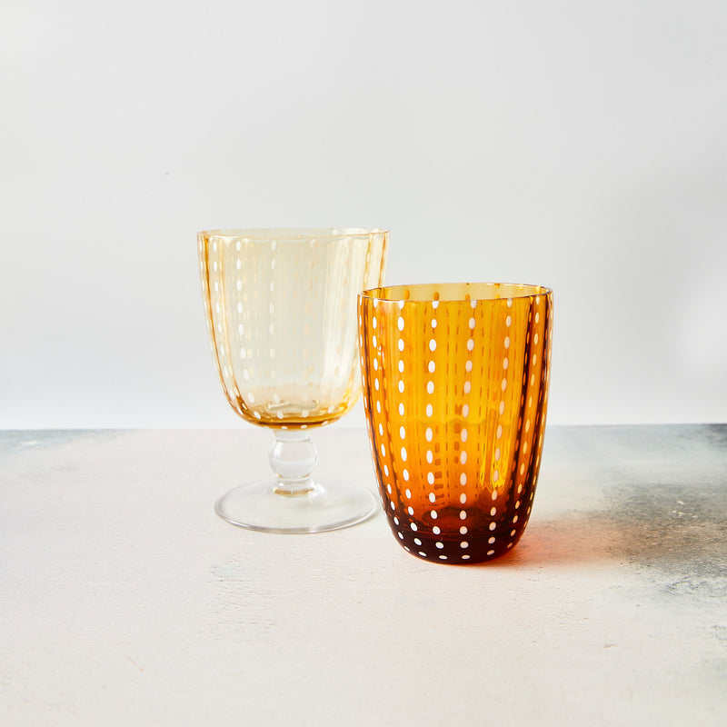 Clear amber and white dotted tumbler and wine glass.