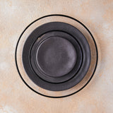Black halo and black plate table setting on peach mixed background.