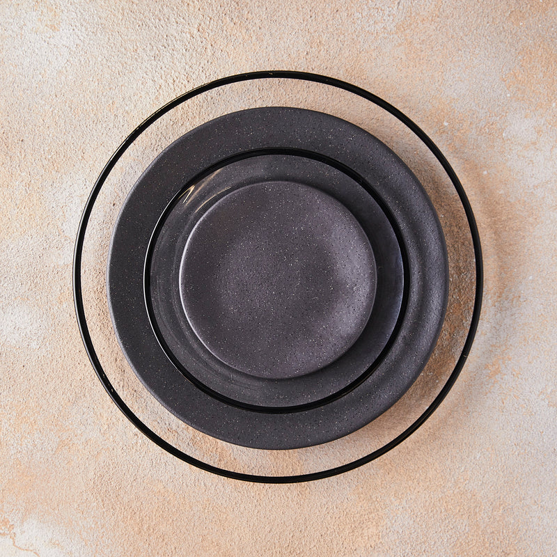 Black halo and black plate table setting on peach mixed background.