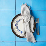 Top view of dark brown, white and white with garland mixed plate set with light grey napkin on blue tile background.