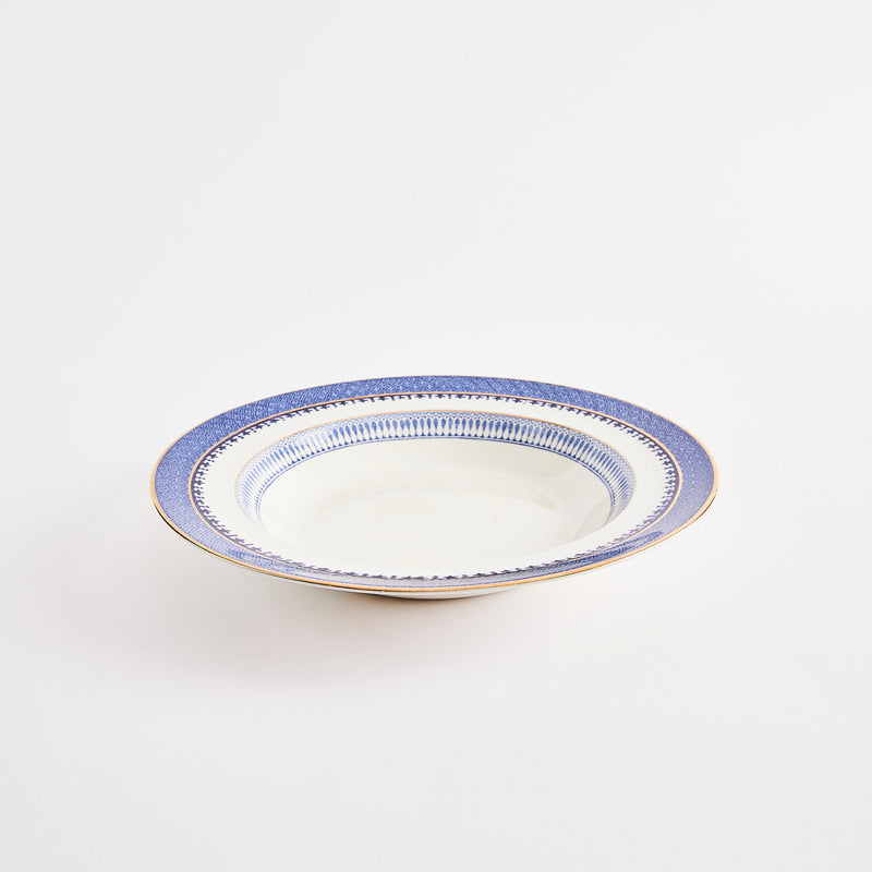 White bowl with blue designed edge and gold rim.