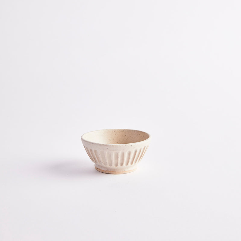 White bowl with indented lines on the exterior side.