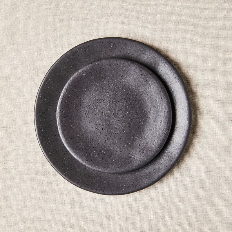 Black with white speckles plate set on cream tablecloth.