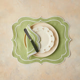 Top view of table setting with green napkin and placemat on beige background.