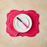 Top view of white table setting with silver and pink handle cutlery, pink napkin and placemat.