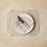 Top view of table setting with light brown napkin and placemat on beige background.