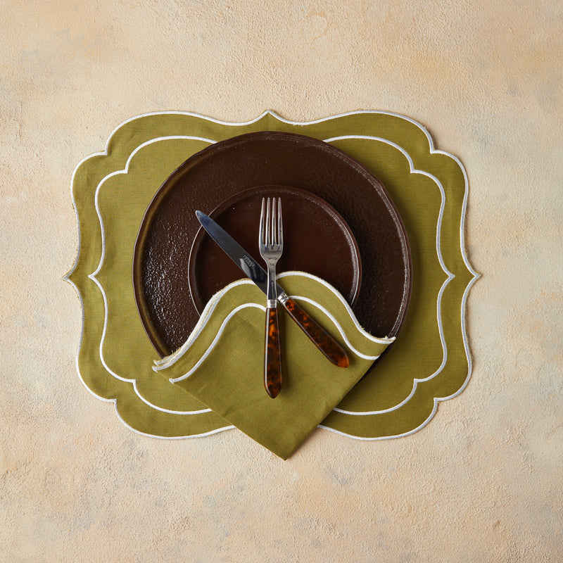 Top view of brown table setting with olive green napkin and placemat on beige background.