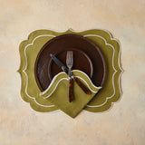 Top view of brown table setting with olive green napkin and placemat on beige background.