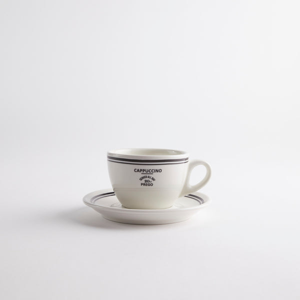White with black edges coffee cup on saucer with "cappuccino served all day 20 cl prego" text on cup.