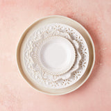 Top view of white and cream mixed plates on pink background.