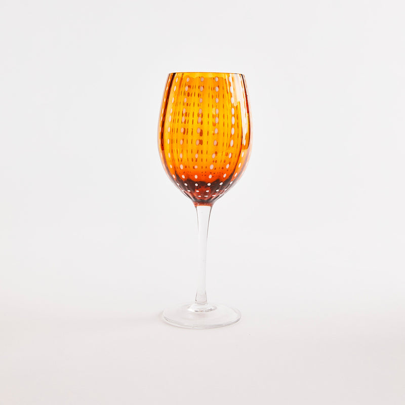Orange with white dotted design wine glass with clear base.