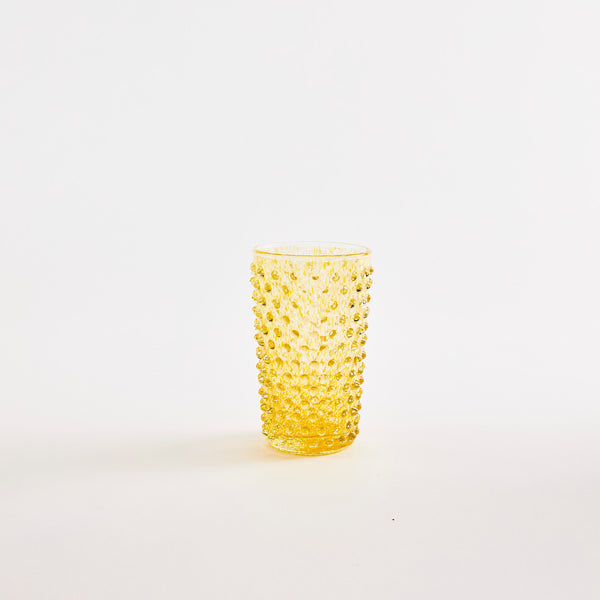 Yellow glass tumbler with bubble embossed design.