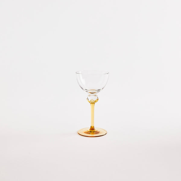 Clear wine glass with yellow stem.