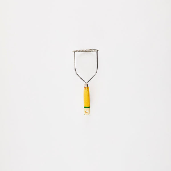 Silver masher with yellow handle.