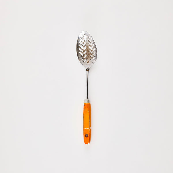 Silver slotted kitchen spoon with orange handle.