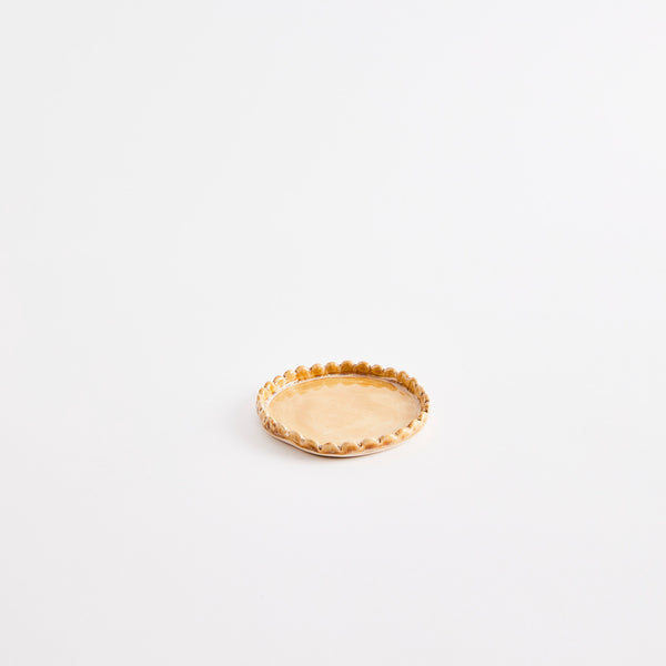 Light brown flat pinch pot with scalloped edges.