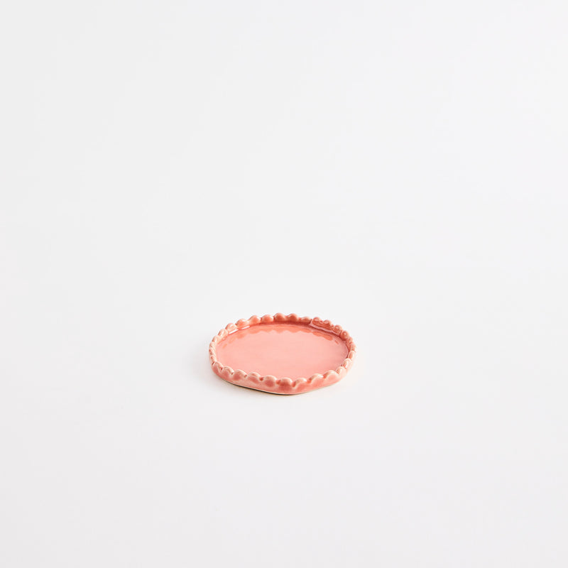 Peach flat pinch pot with scalloped edges.