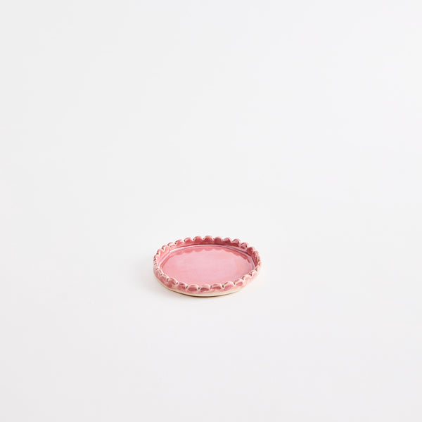 Pink flat pinch pot with scalloped edges.