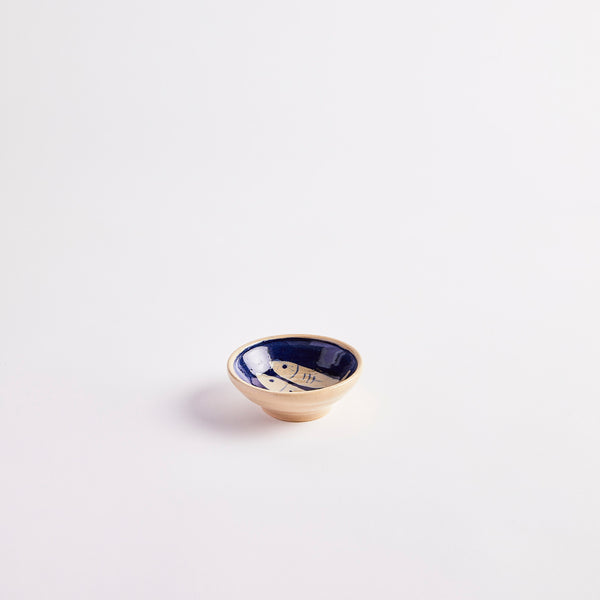 Cream with navy detailing of two fish inside pinch pot. 