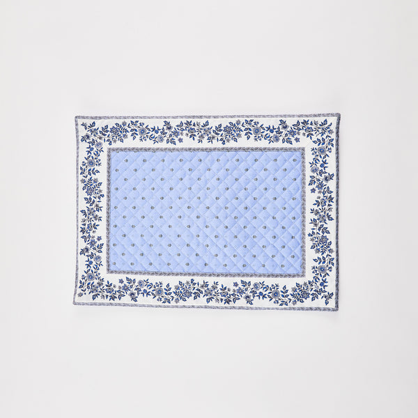 Blue quilted placemat with floral border.