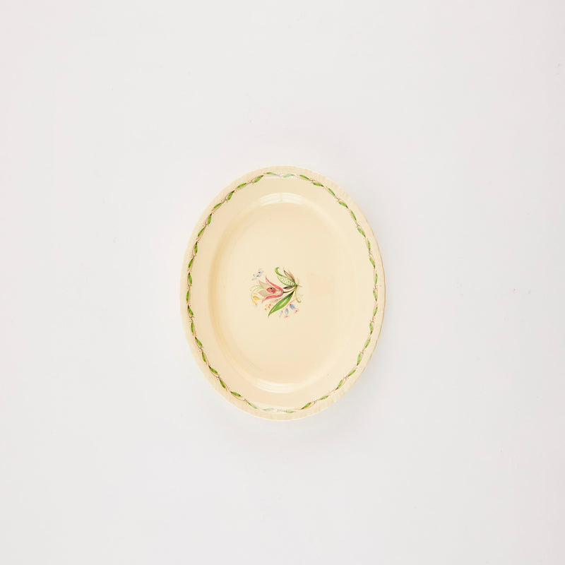 Oval cream platter with flower in middle and greenery edge.